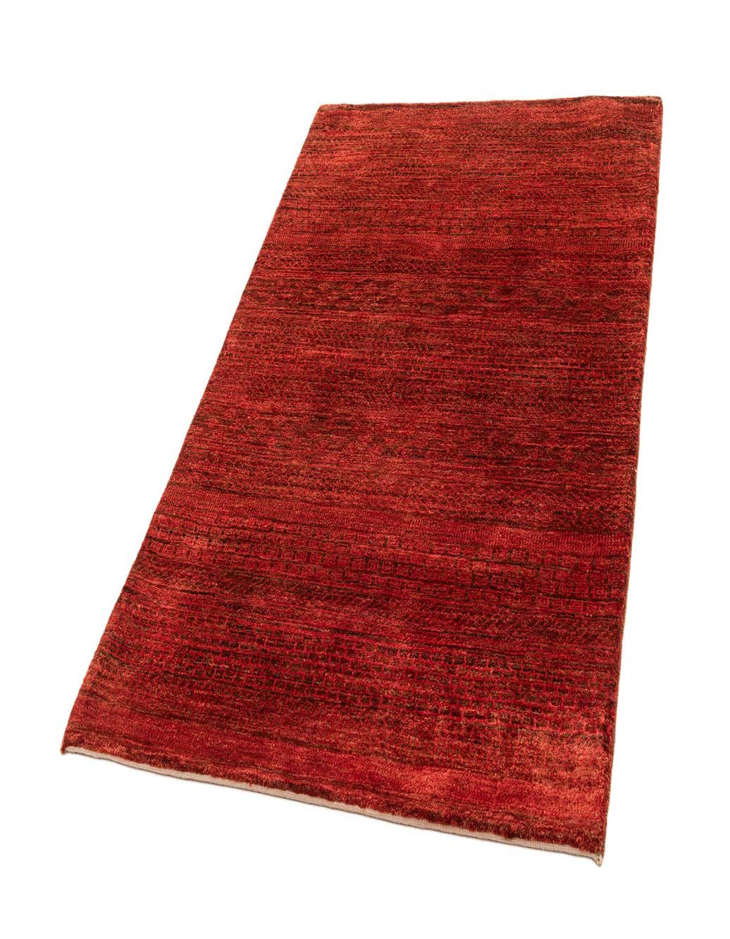 A 4x6 rectangular handmade wool rug in varying shades of red, showcasing its medium pile texture.