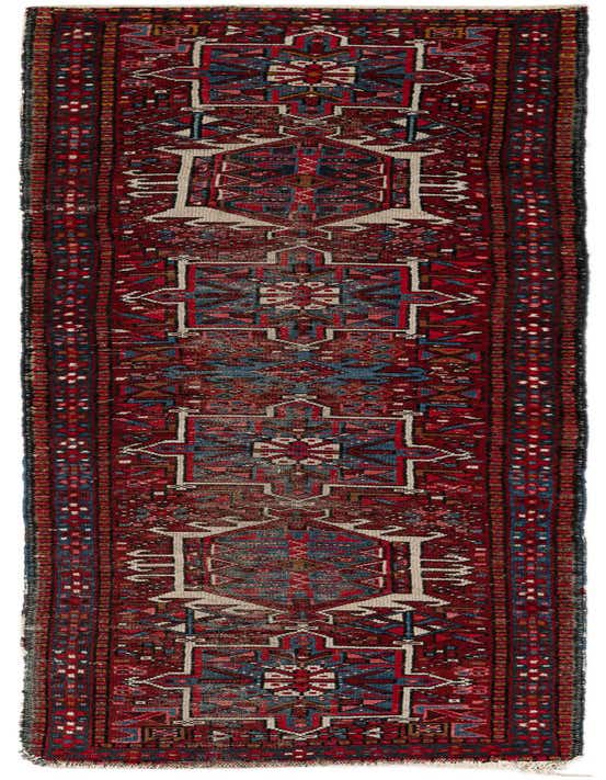 A 9 ft runner rug in traditional Persian style with a deep red background and intricate tribal patterns in blue, cream, and brown.