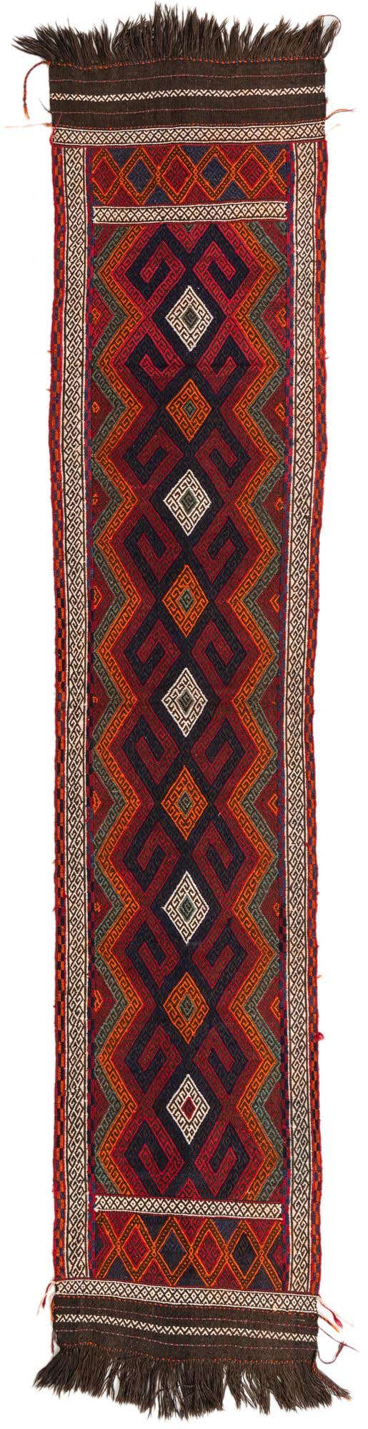 A 10 ft Kilim Fars runner rug with a tribal geometric pattern in shades of red, navy, and orange, featuring fringe.
