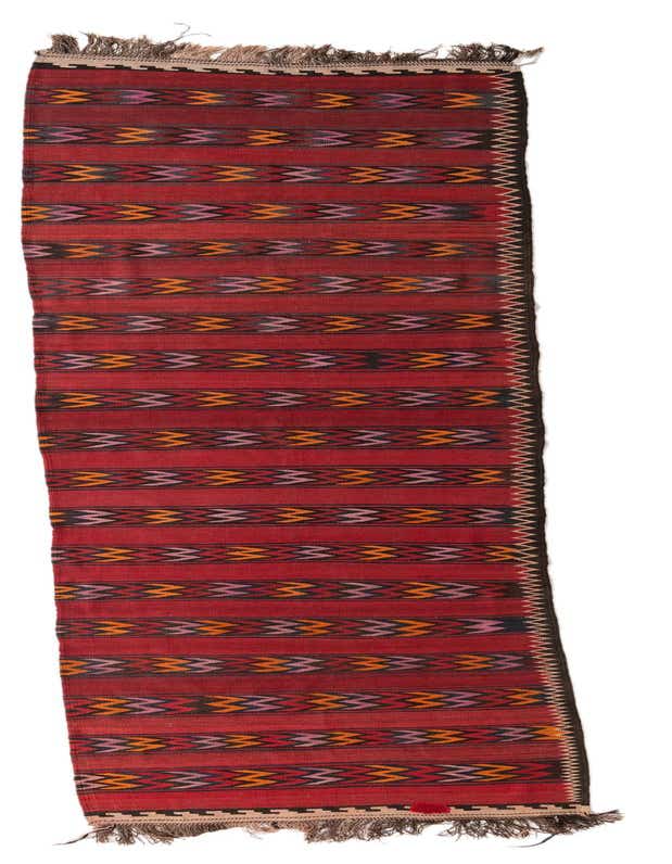 A 15 ft Kilim Fars runner rug with a red background and horizontal stripes featuring tribal patterns in orange, pink, and black.