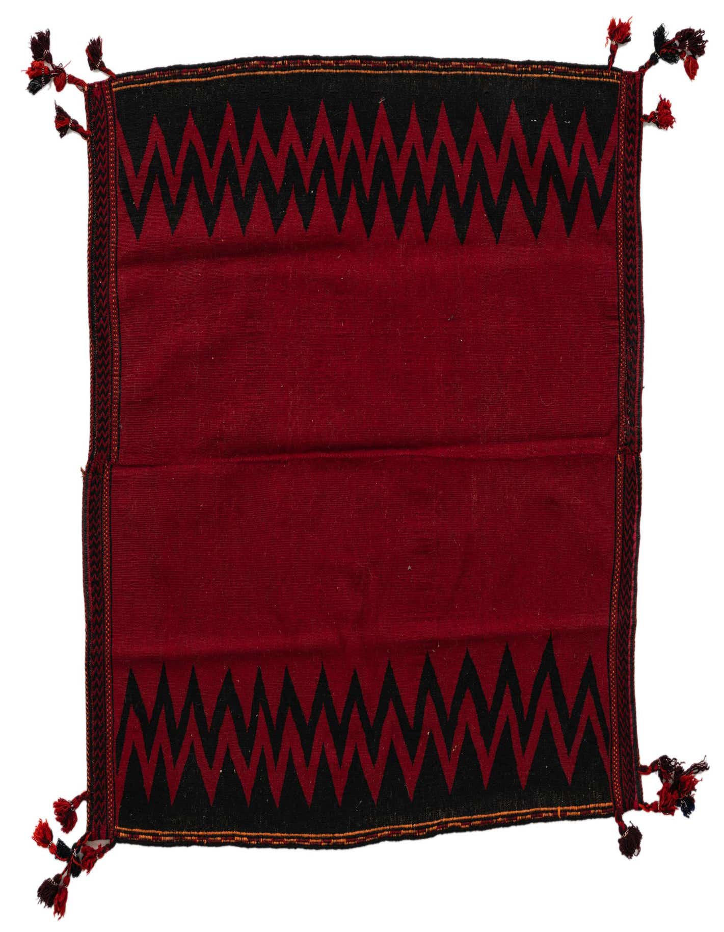 A square 4' 0 x 4' 2 red wool flatweave rug with black tribal zigzag patterns and corner tassels.