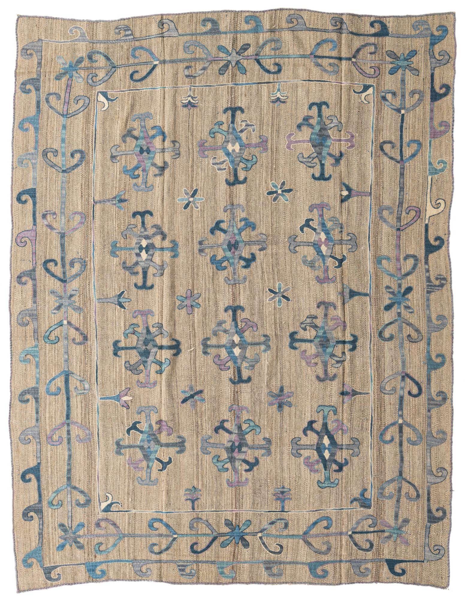 A 6x9 rectangular Kilim Suzani rug featuring a tan background with blue, purple, and cream tribal patterns.