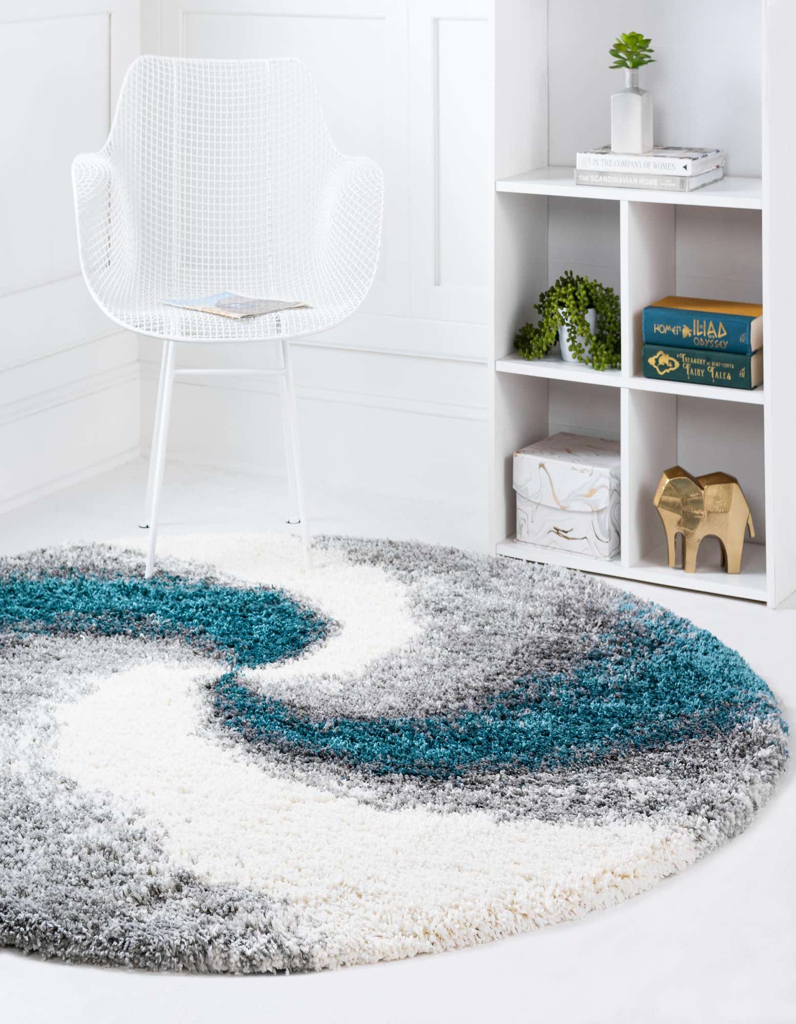 A round, plush shag rug featuring an abstract swirl pattern in shades of teal blue, grey, and white.