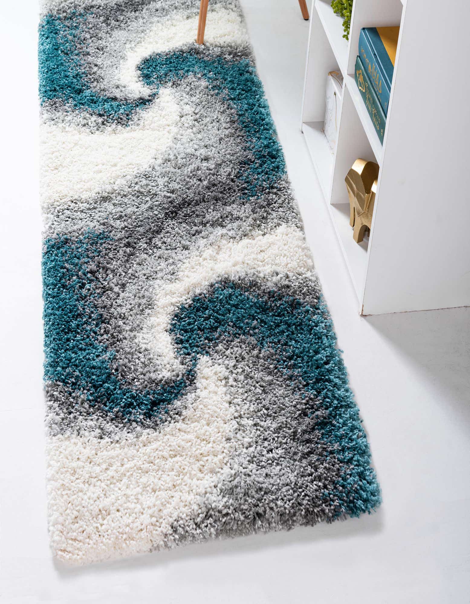 A soft, plush 7 ft runner rug featuring an abstract pattern in varying shades of blue, grey, and cream.