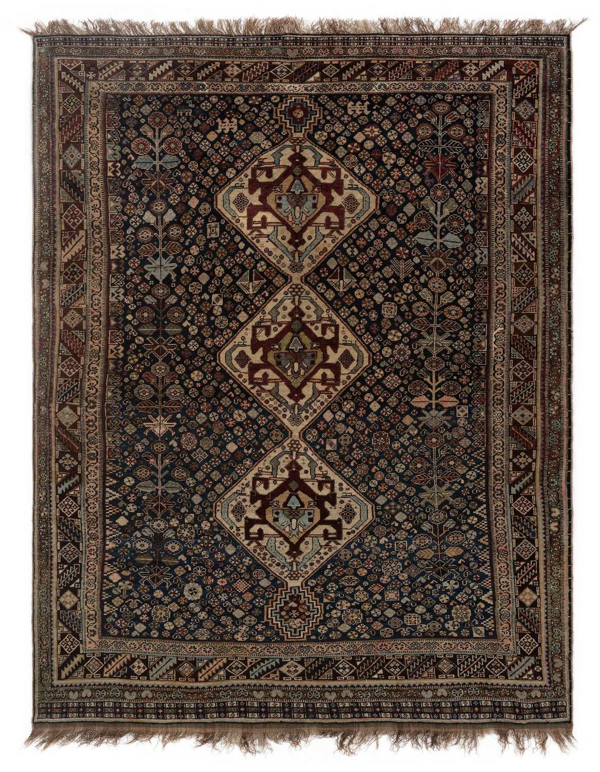 A 5x8 rectangular Ghashghai Persian rug in whites with a dark blue background and intricate traditional patterns, handmade from wool.